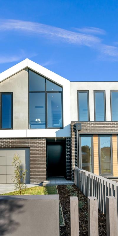 Contemporary two-story house with large windows, a mix of brick and concrete, and a minimalist front yard.